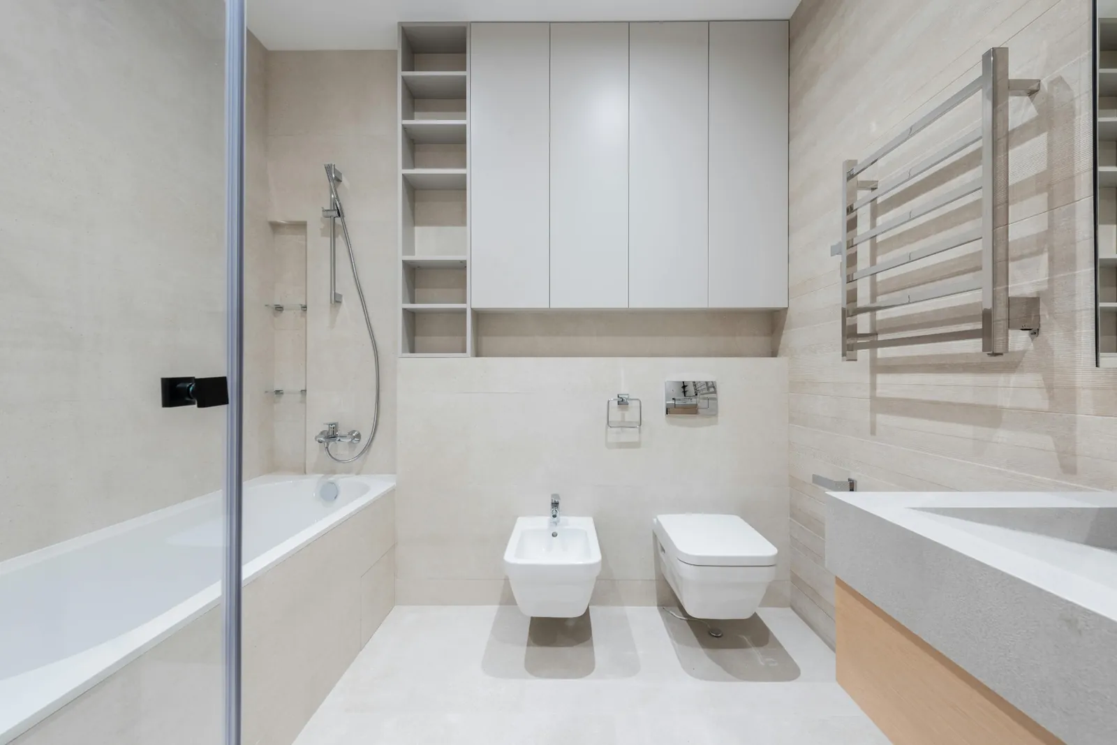 Light beige bathroom with tub, wall-hung fixtures and integrated storage