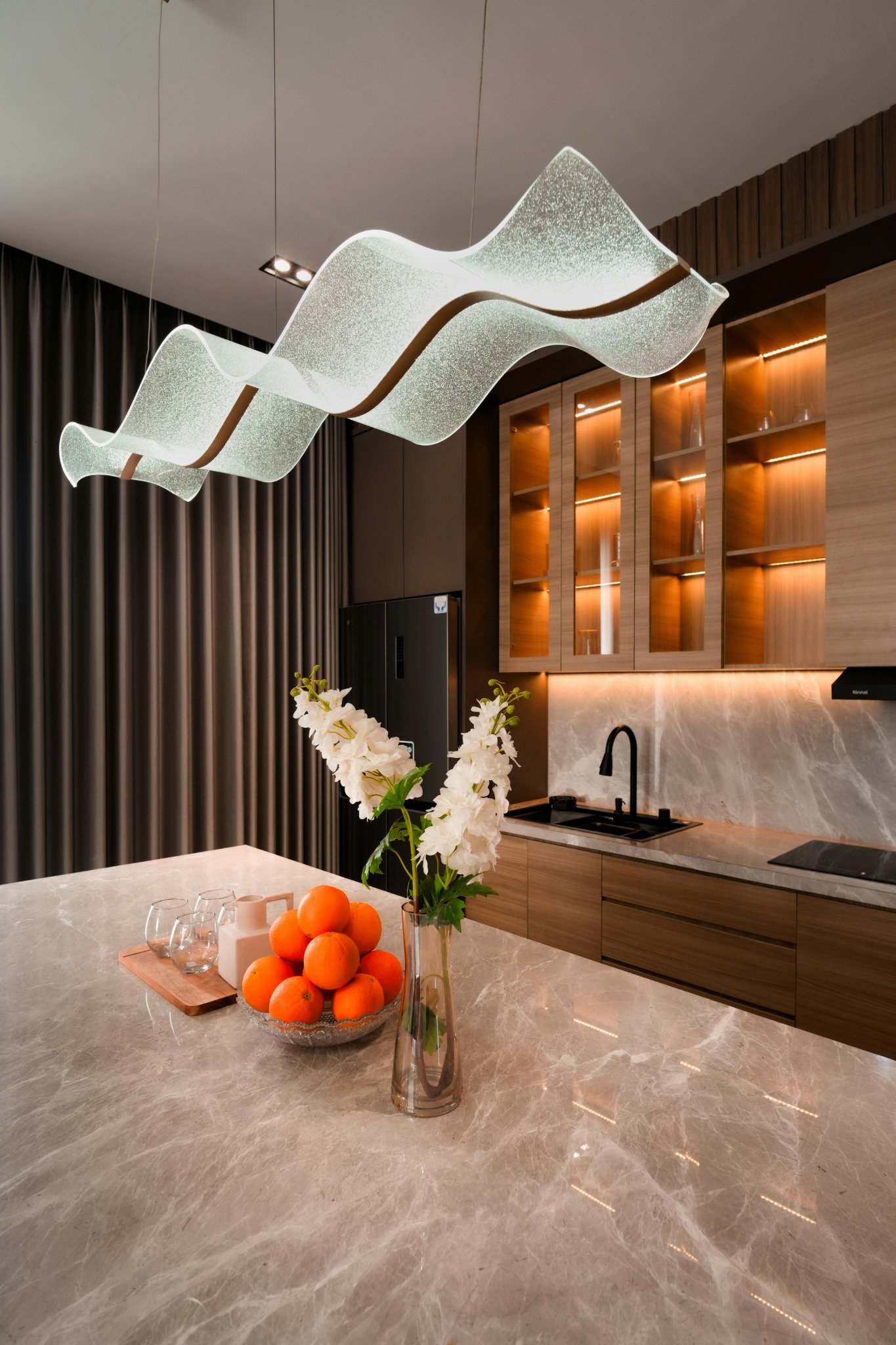 Fir Stone quartz kitchen island with light wood cabinets and modern lighting