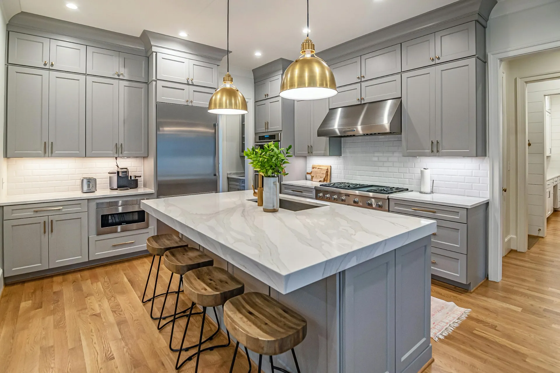 Bright kitchen with white marble-look quartz island and gold pendants